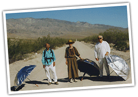Dinesh, Joy, and Warren on the road with their umbrellas beside them