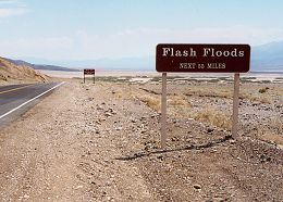 Highway sign reading 'Flash Floods Next 55 Miles'