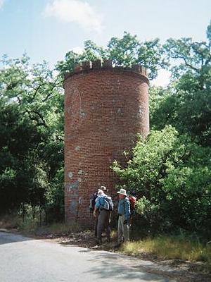 hikers next to a cylindrical brick tower about 20 feet tall