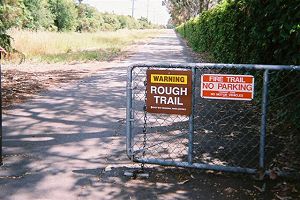 sign warning of rough trail leading to smoothly-paved trail