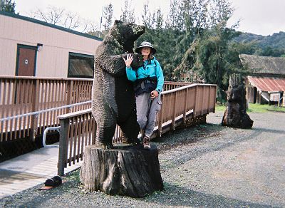 Joy with a bear sculpture made from a tree trunk