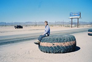 Joy sitting on a large truck tire being employed as a traffic barrier