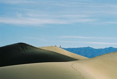 Dunes with footprints leading to two figures on the crest