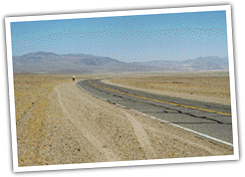 a desolate road with a hiker in the distance