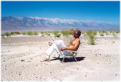 Dinesh, shirtless and sitting on a lawn chair, on the dry bed of Owens Lake
